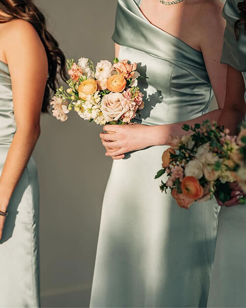 Bridesmaids in light dresses holding flowers